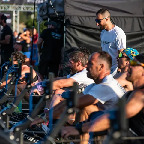 A row of athletes side by side on rowing ergometers.